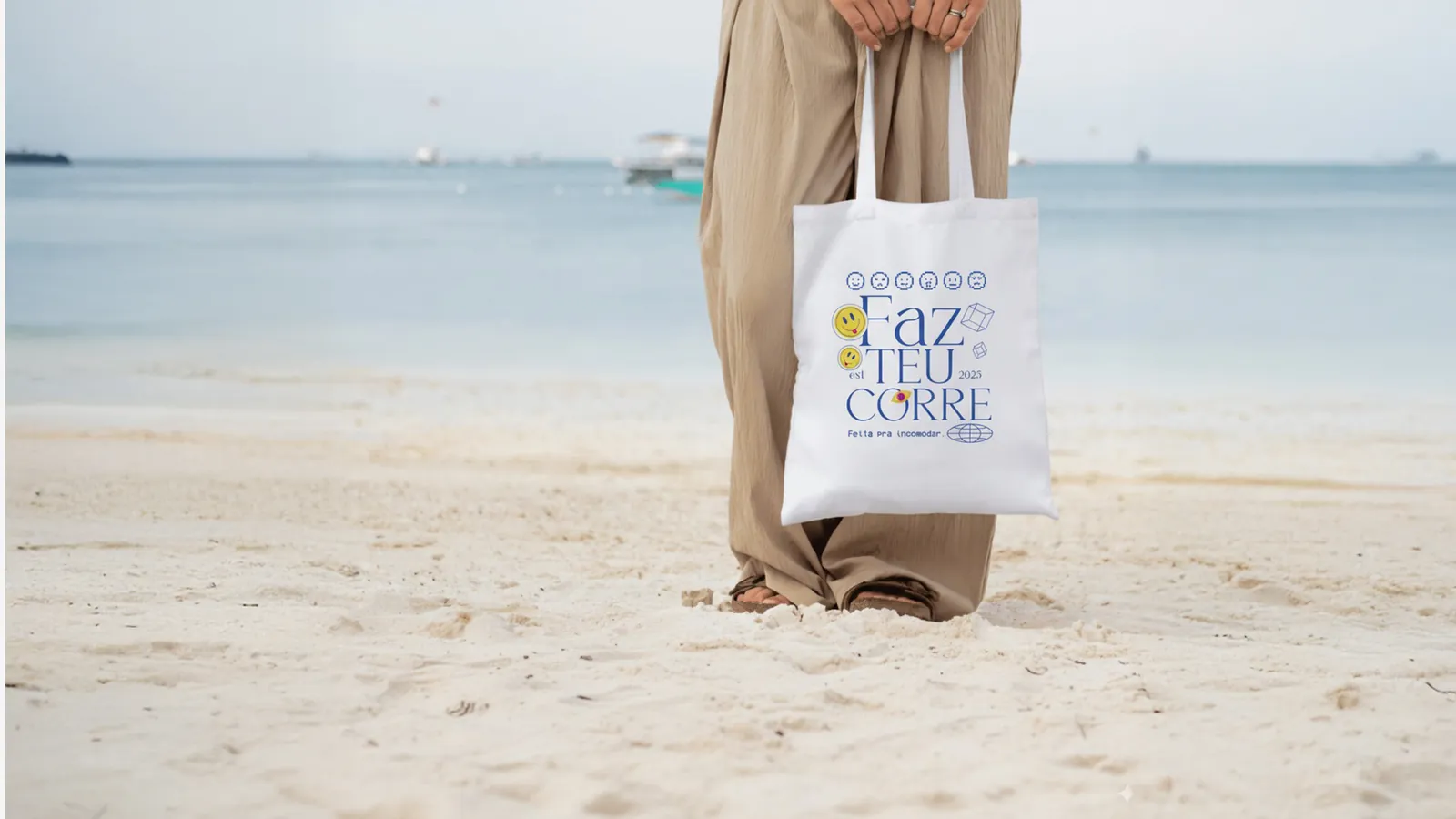Ecobag Faz teu corre segurada na praia, com o mar ao fundo