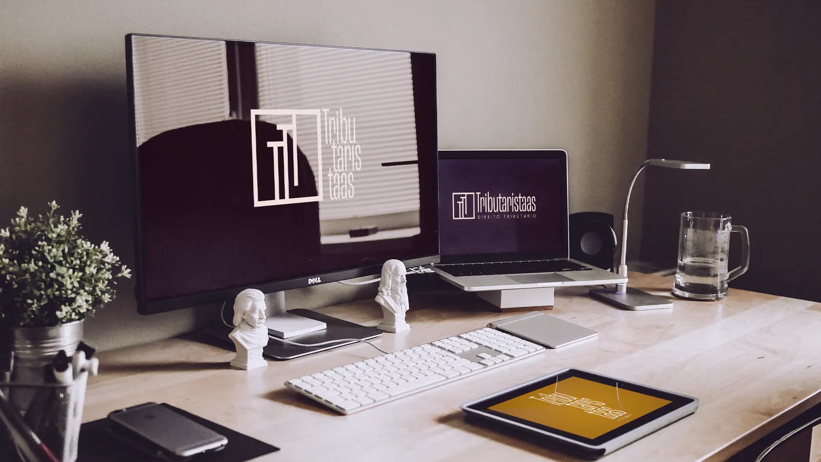 Mesa de trabalho com o logotipo no monitor, no notebook e no tablet
